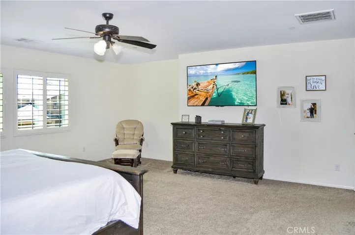 The oversized main bedroom suite sits at the end of the hall upstairs for a little extra privacy and features upgraded plush carpeting, louvered shutters, a ceiling fan, dual walk-in closets, and an en suite bath. There's plenty of room for a retreat area, too.