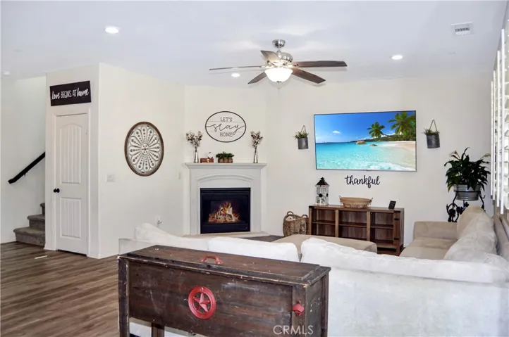 The living room area offers a cozy gas fireplace, waterproof luxury vinyl plank flooring, a ceiling fan, recessed lighting and lots of windows looking out on the backyard