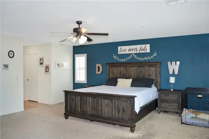 The oversized main bedroom suite sits at the end of the hall upstairs for a little extra privacy and features upgraded plush carpeting, louvered shutters, a ceiling fan, dual walk-in closets, and an en suite bath. There's plenty of room for a retreat area, too.