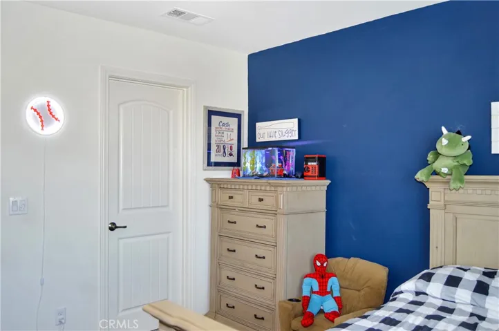 The 2nd bedroom upstairs is down the hall from the main suite and features a walk-in closet, ceiling fan, window blinds, and fun blue accent wall