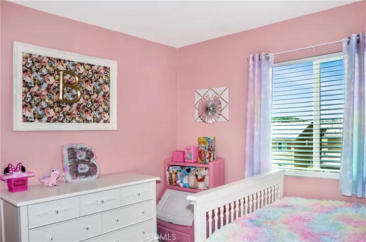 The 3rd bedroom is on the other side of the loft from the first two bedrooms, offers a walk-in closet, window blinds, a ceiling fan, and pretty pink paint