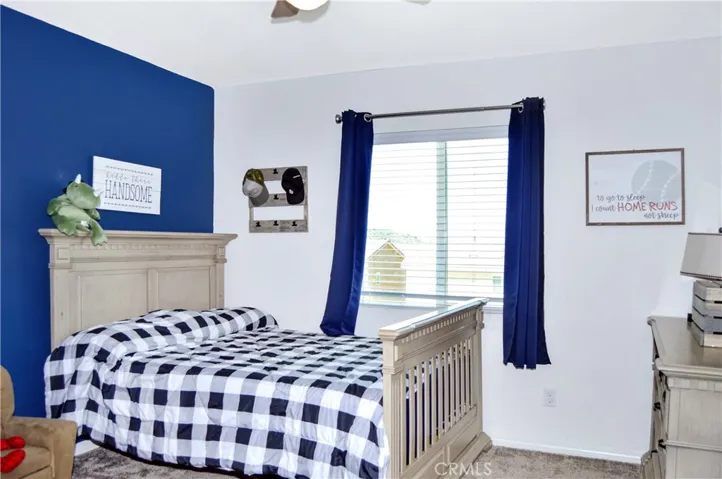The 2nd bedroom upstairs is down the hall from the main suite and features a walk-in closet, ceiling fan, window blinds, and fun blue accent wall