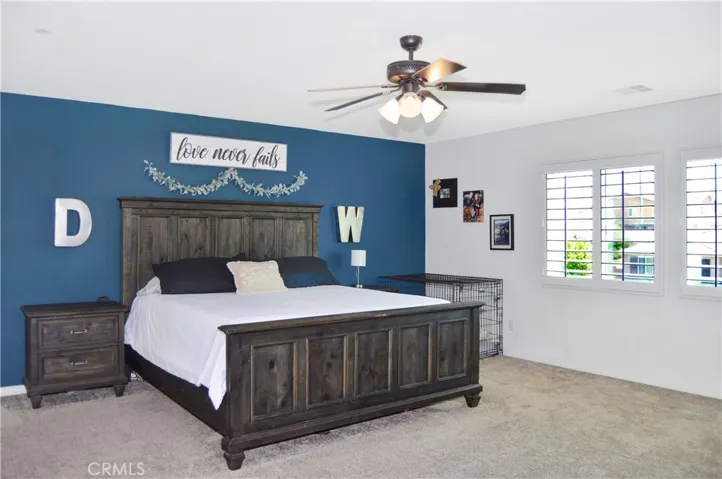 The oversized main bedroom suite sits at the end of the hall upstairs for a little extra privacy and features upgraded plush carpeting, louvered shutters, a ceiling fan, dual walk-in closets, and an en suite bath. There's plenty of room for a retreat area, too.