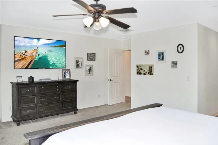 The oversized main bedroom suite sits at the end of the hall upstairs for a little extra privacy and features upgraded plush carpeting, louvered shutters, a ceiling fan, dual walk-in closets, and an en suite bath. There's plenty of room for a retreat area, too.