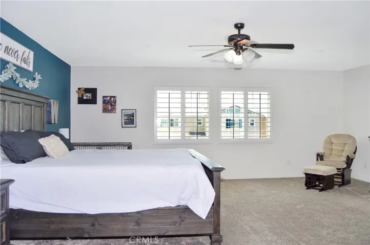 The oversized main bedroom suite sits at the end of the hall upstairs for a little extra privacy and features upgraded plush carpeting, louvered shutters, a ceiling fan, dual walk-in closets, and an en suite bath. There's plenty of room for a retreat area, too.