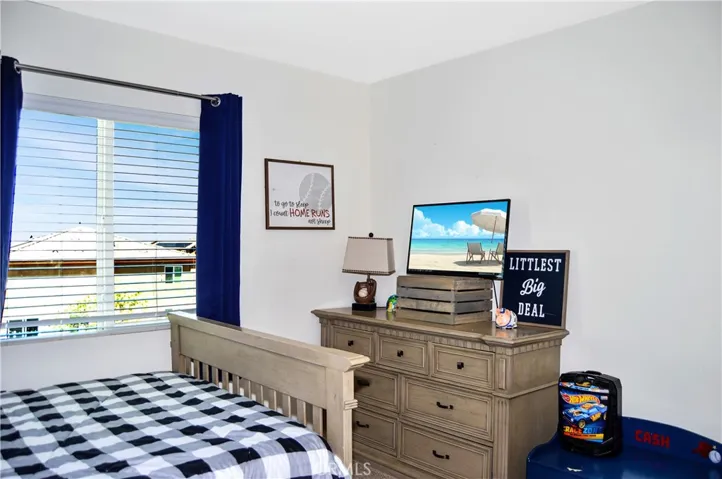 The 2nd bedroom upstairs is down the hall from the main suite and features a walk-in closet, ceiling fan, window blinds, and fun blue accent wall