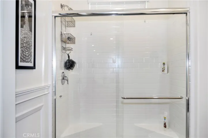 The 3rd bath is on the main floor and provides a walk-in shower, wainscoting accents, dark cabinetry, and more luxury vinyl plank flooring that guests are sure to love