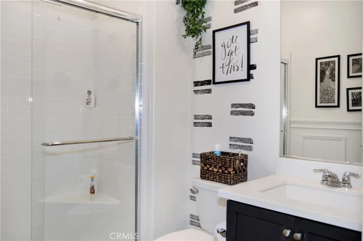 The 3rd bath is on the main floor and provides a walk-in shower, wainscoting accents, dark cabinetry, and more luxury vinyl plank flooring that guests are sure to love