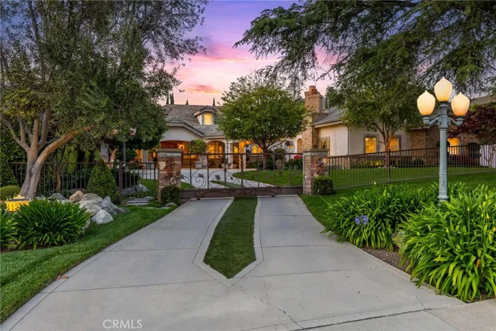 Stunning landscaping with a gated entry leads up to a sweeping driveway.