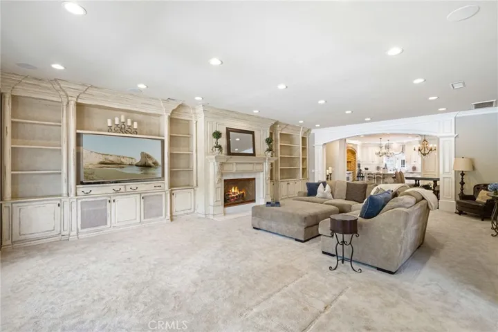 Family room with built-ins, a fireplace, and open kitchen.