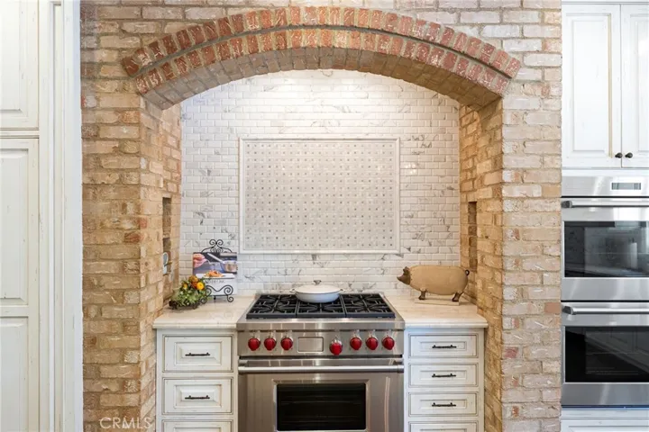 Arched brick work frames the six-burner Wolf range.