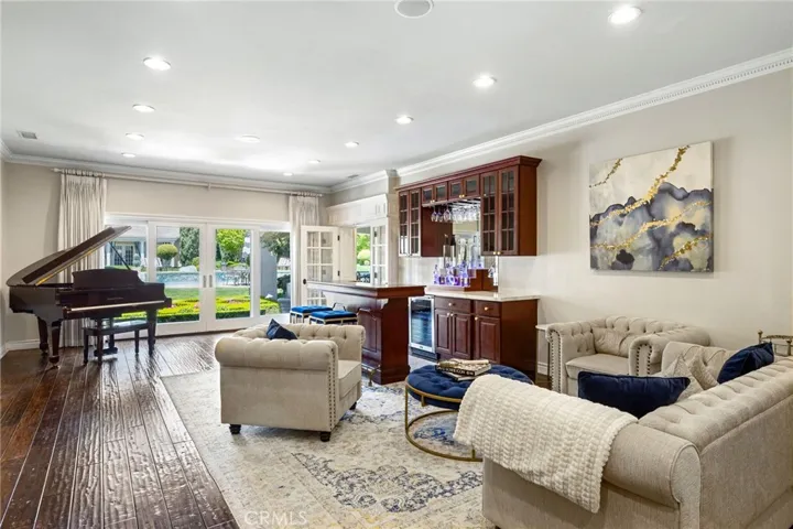Living room offering engineered hardwood flooring, crown molding, a custom built bar, and sliding doors that lead to the backyard.