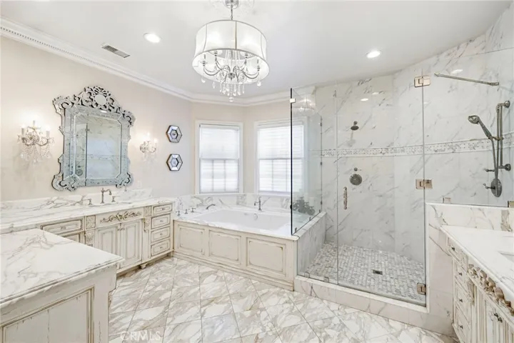Custom finished bathroom with dual sinks, soaking tub, and separate shower with a frameless glass enclosure.