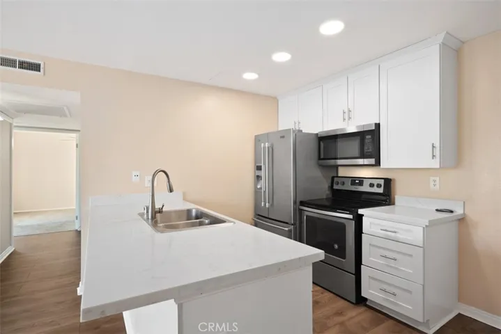 Another view from the front door when you walk in to see the kitchen that has been remodeled a few years ago with resessed lighting, stainless steel appliances, quartz counter tops, satin nickel fixtures.