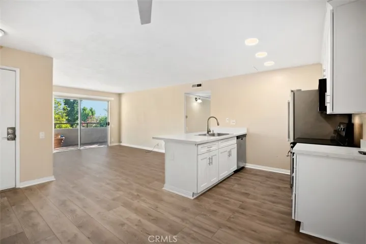 This is the view from the dining room past the kitchen, Living room to the balcony.  Newer vinyl flooring.