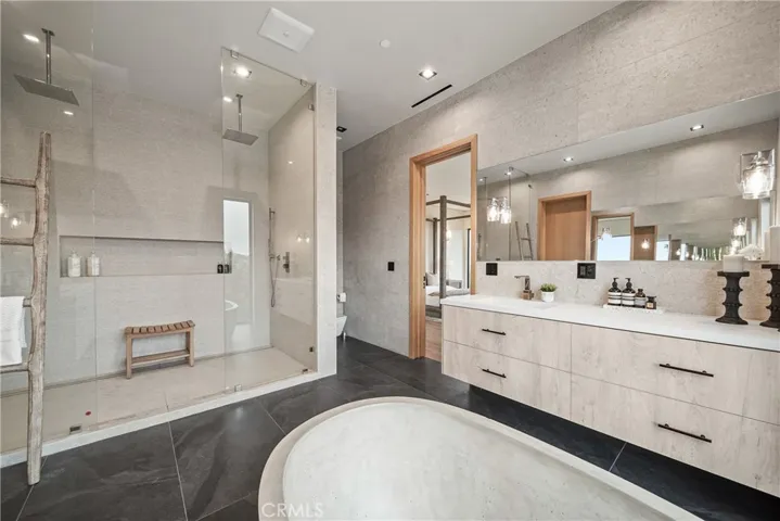 Primary Bathroom includes two separate vanities, a tub and rain showers.