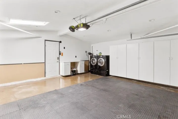 Skylighted garage with a washer and dryer with a water softener and work area.