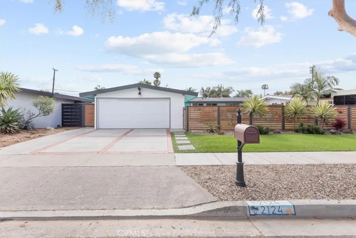 Closer street view of driveway and fenced front yard