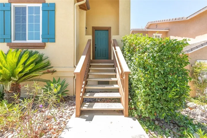 Step into this home through a charming entrance surrounded by lush greenery and vibrant plants.