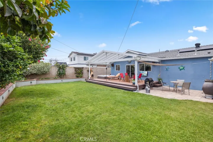 Spacious Backyard Oasis: Covered deck, lush lawn, and  and fruit-bearing trees