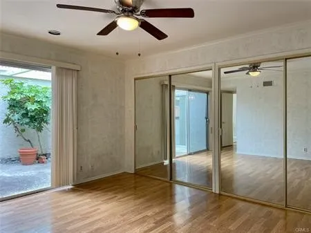 Large Master suite with an entire wall of mirrored wardrobes, ceiling fan and sliding door....Looks out on the ATRIUM....