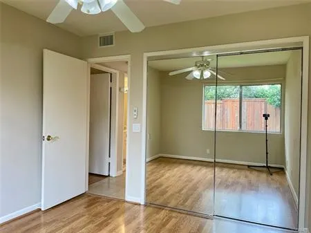 Second bedroom with mirrored wardrobes and a ceiling fan....window looking outside.