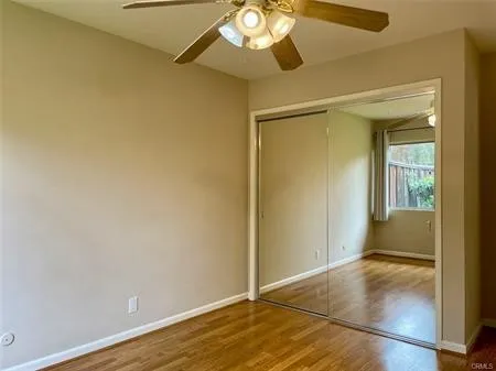 Second bedroom with mirrored wardrobes and a ceiling fan.