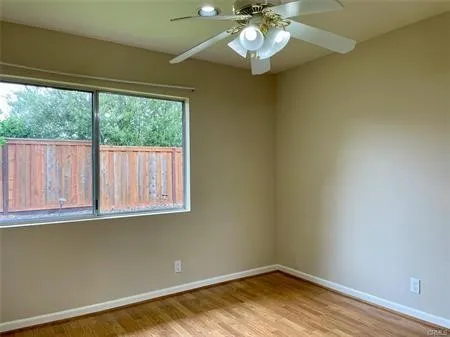 Second bedroom with mirrored wardrobes and a ceiling fan.....window looking outside.