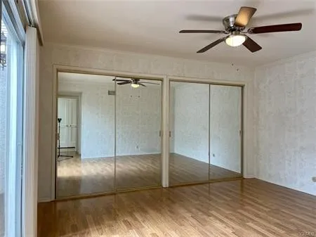 Large Master suite with an entire wall of mirrored wardrobes, ceiling fan and sliding door....Looks out on the ATRIUM....