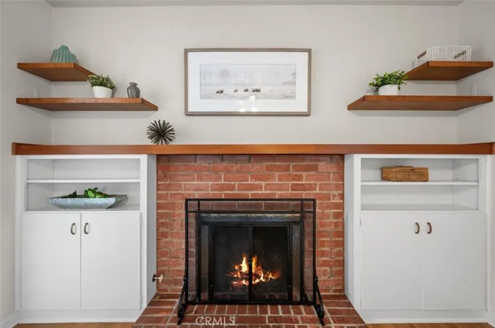 Masonry wood burning fireplace with gas starter flanked with built-ins and open shelves.