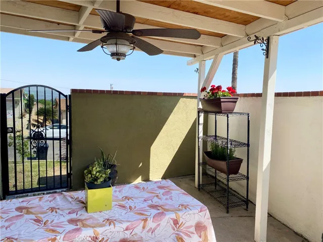 Covered patio area with ceiling fan/light and gate to front yard