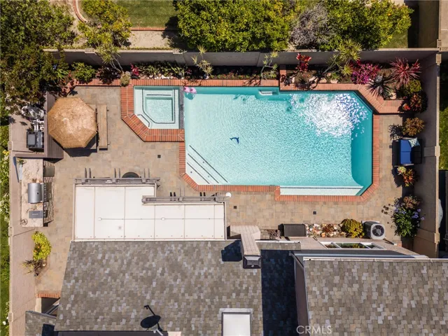 Aerial photo highlights the spacious backyard with pool, hot tub, and pergola.
