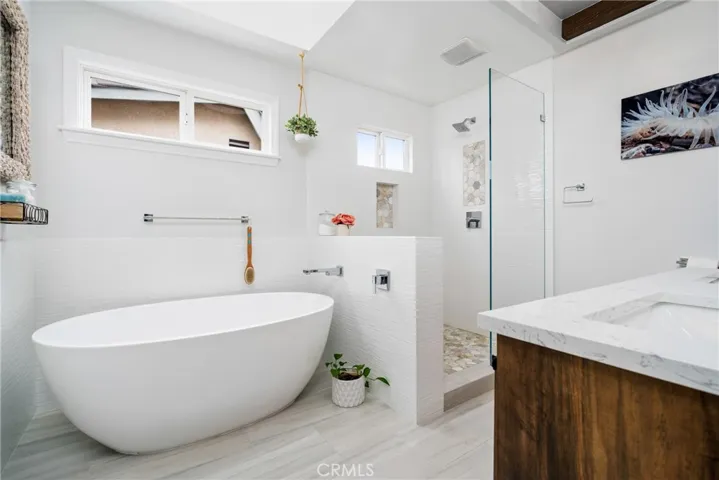 Enjoy the spa-like vibe of the beautifully remodeled en-suite bathroom with tile floors, a sitting tub, and a step-in shower featuring accented tiles and high-end finishes.




