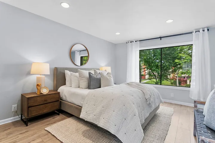 Primary bedroom with huge window overlooking greenbelt in front of the home.
