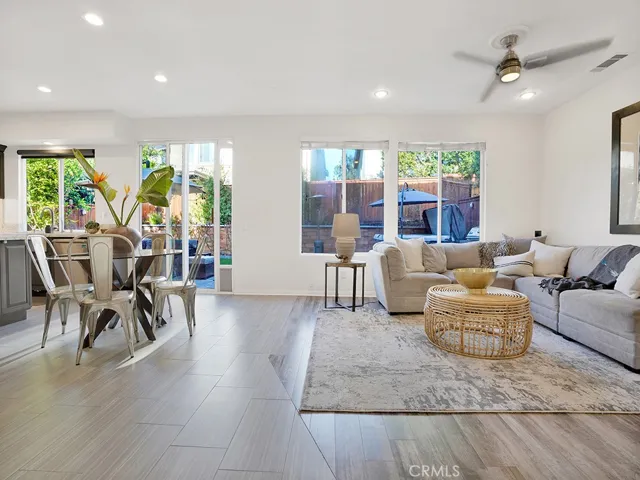 Large family room that overlooks the kitchen and breakfast dining table complete with gas fireplace, freshly painted, wood blinds, a beautiful view of the backyard, built-in TV cabinet, and modern ceiling fan.