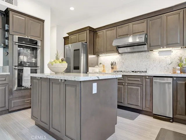 Large Island for the prepping and serving complete with storage, double over, trash compactor, gas cooktop, sleek professional style range hood.
