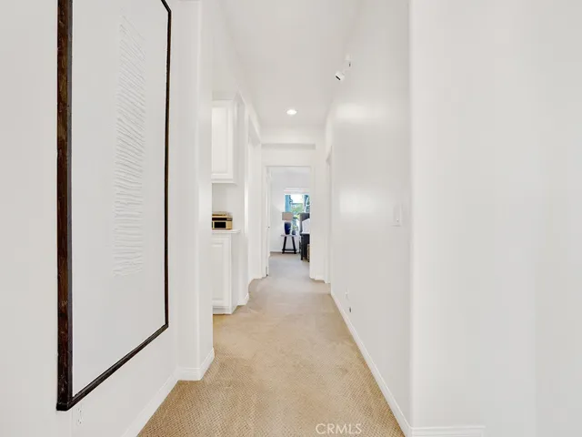 View from the 5th bedroom at the top of the stairs down the hall to the primary suite. Large walkways with premium carpet. Freshly painted with recessed lighting.