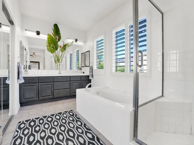 Primary Bath complete with HUGE walk-in closet to the left, soaking tub, shower, modern light fixtures, beautiful shutters. Double sinks. Plenty of space to get ready and relax.