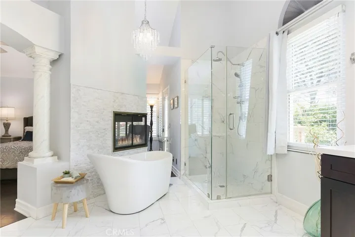 The spa-like primary bathroom looks like a photo from a magazine! Marble flooring, walk in shower with frameless glass doors, and an oval soaking tub next to the 2-sided fireplace.