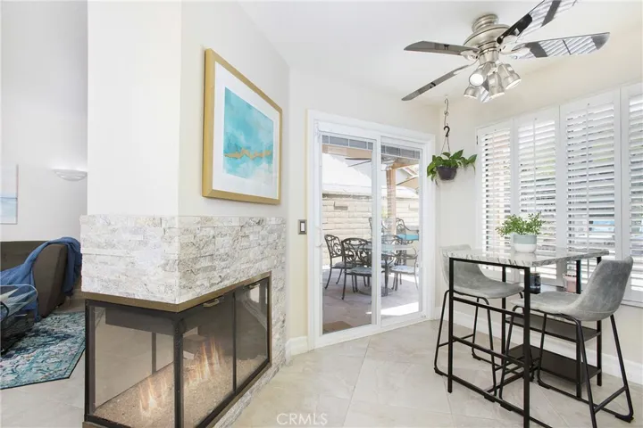 Separate informal eating area with a double-sided fire place, ceiling fan, and sliding glass doors to the back yard.