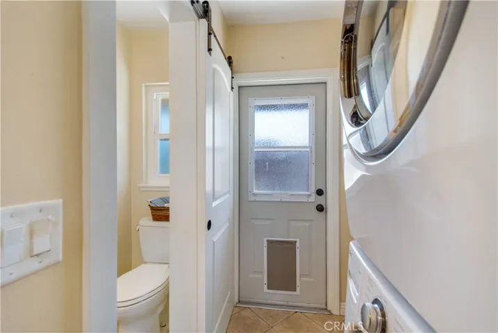 Laundry room with stacked washer and dryer, rear entry and guest bathroom.