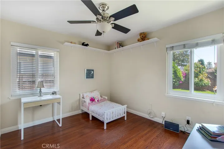 2nd bedroom with windows facing back yard and side run of home, included is ceiling fan and custom shelving.