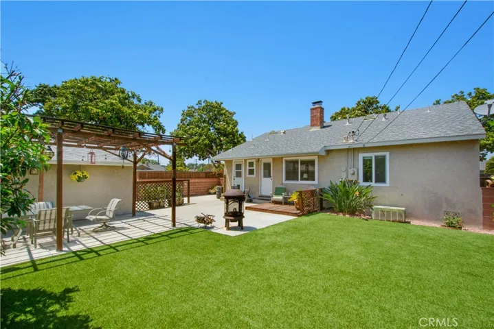 Back yard including artificial grass and view of back of home.