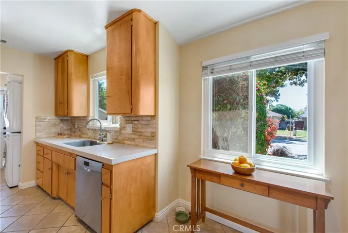 Beautiful kitchen cabinetry with unique rounded off corners on cabinets above Corraine counters, including stone type subway tiles and windows to allow natural light to flood in.