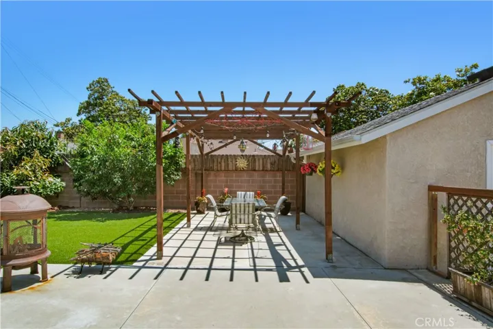 Day time view of pergola set in back yard, cinder block privacy wall including treated wood extended at top of block wall for added privacy.