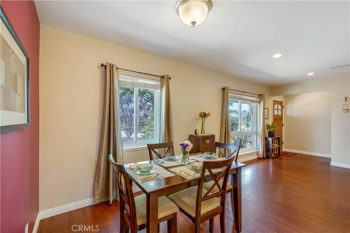 View from cute kitchen onto dining and living space with large windows facing front yard.