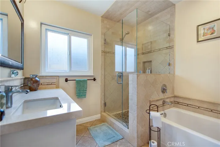 Hallway bathroom including matching well maintained tile and Corian countertop, a comfortable sized walk-in shower and a tub for soaking.