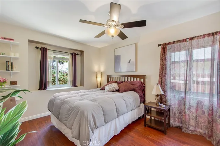 Primary bedroom, including unique recessed window facing front yard and side window facing side run of home and custom shelving and ceiling fan.