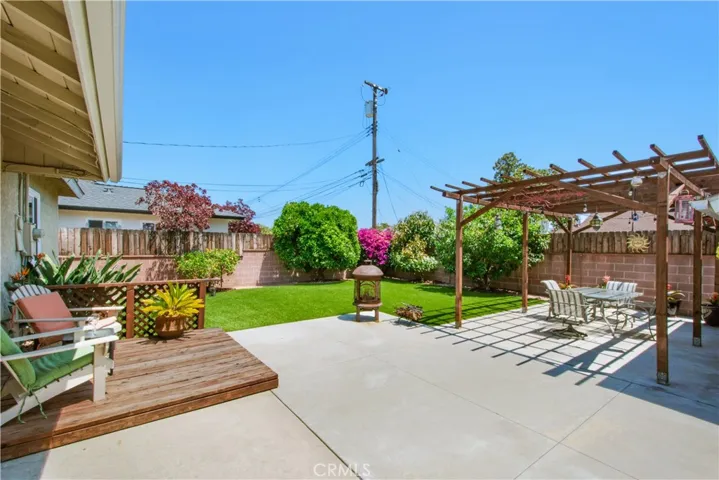 View of back yard including small back wooden deck to set your chairs to enjoy view of your beautiful Orange tree, Lemon bush, Bougainvillea bush in bloom, Avocado tree and Fruit salad tree.