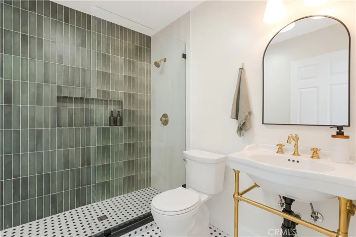 Remodeled bathroom with Victorian green tile, mosaic flooring, and gold fixtures